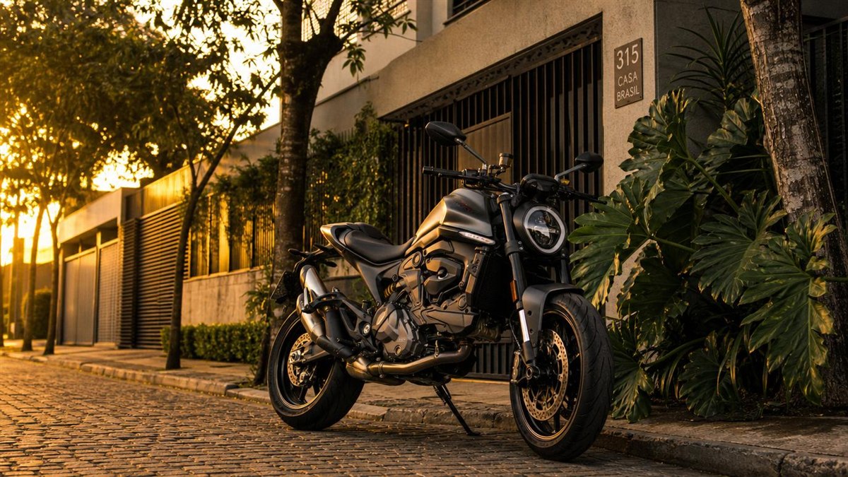 Moto escura estacionada em rua residencial ao golden hour - consorcio Porto moto